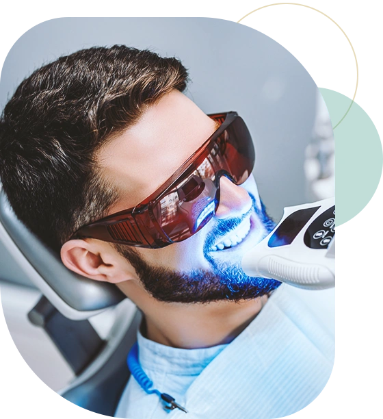 Dentist starting teeth whitening procedure with young man.