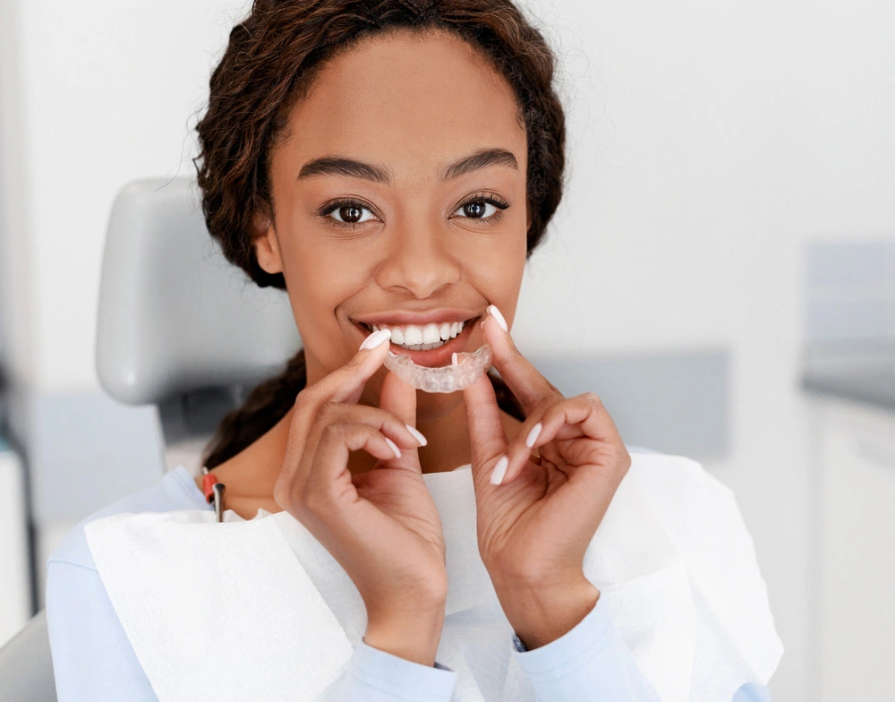 Close up of young black woman holding invisible aligner