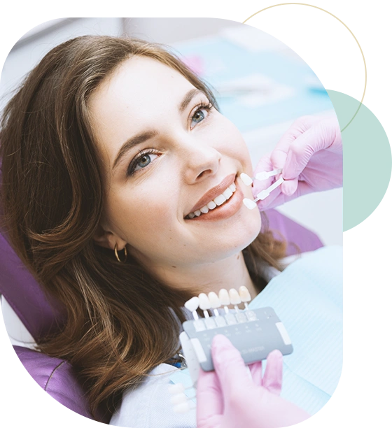 Dentist choosing teeth enamel shade color for young smiling female patient before whitening procedure.